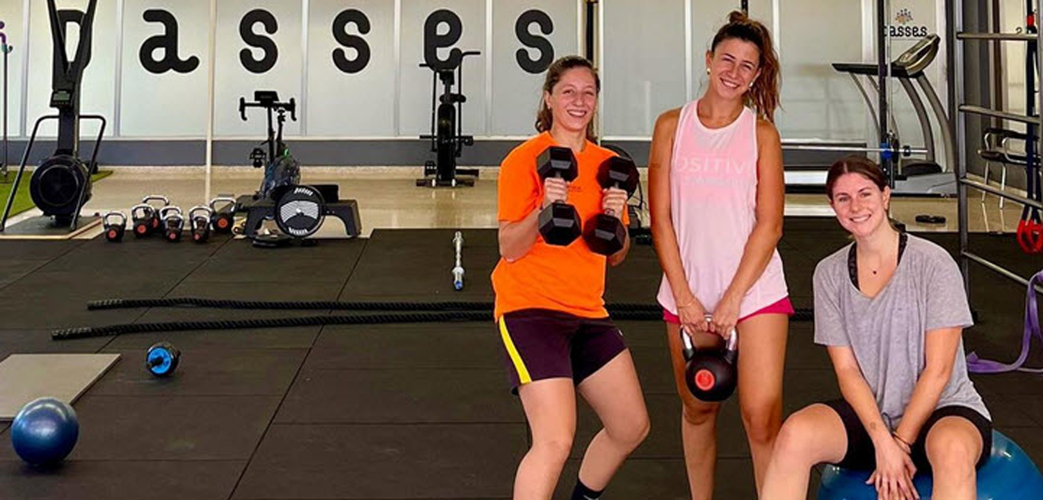 Imagen de tres chicas en el gimnasio sosteniendo unas pesas